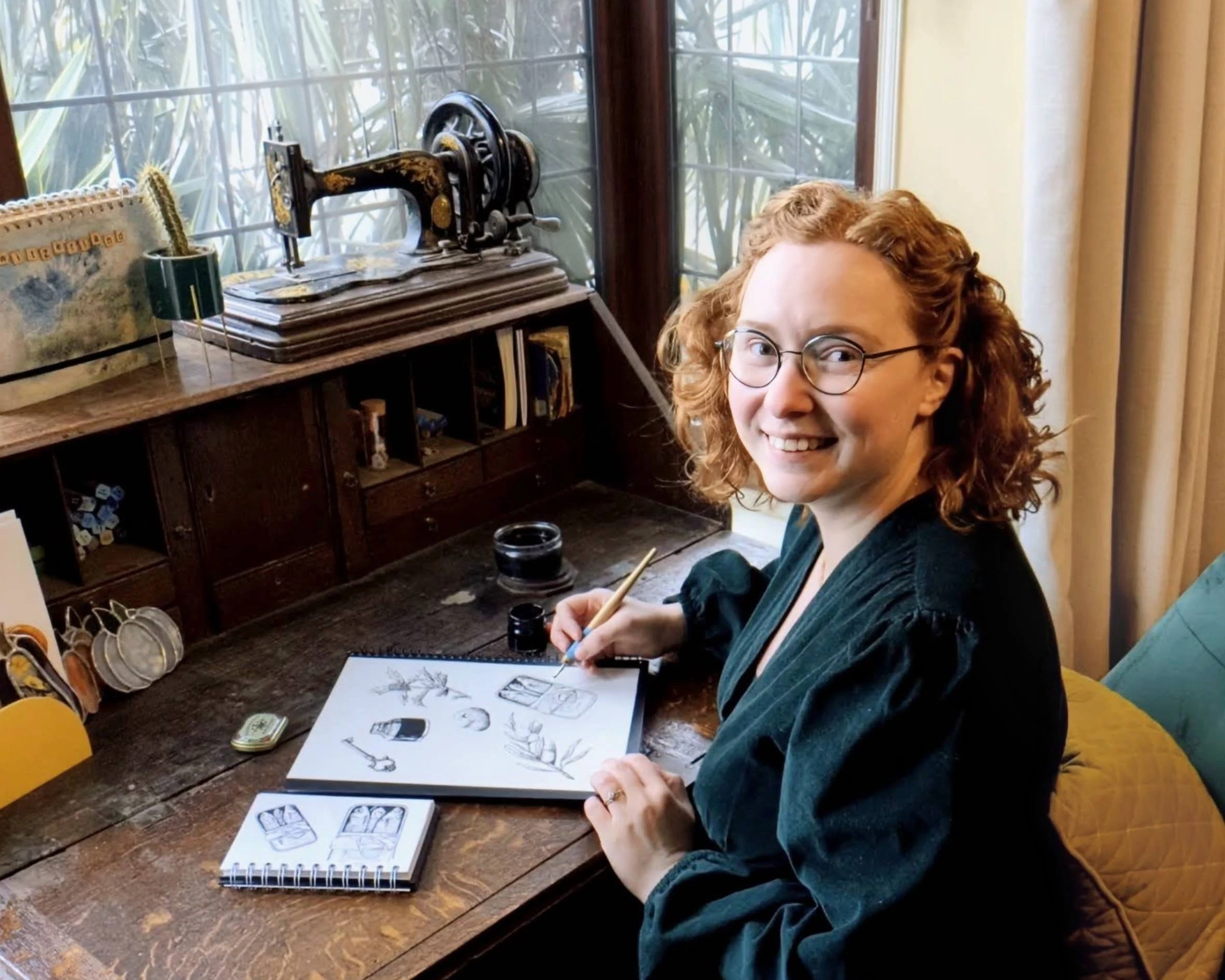Bethanee Kay sat at her desk working on a black and white ink drawing